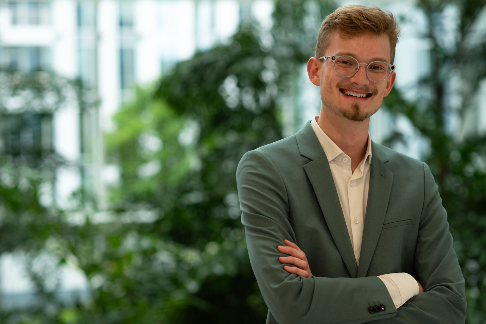 Jan Mára stojící před zelení, usmívajíce se a se složenými rukami